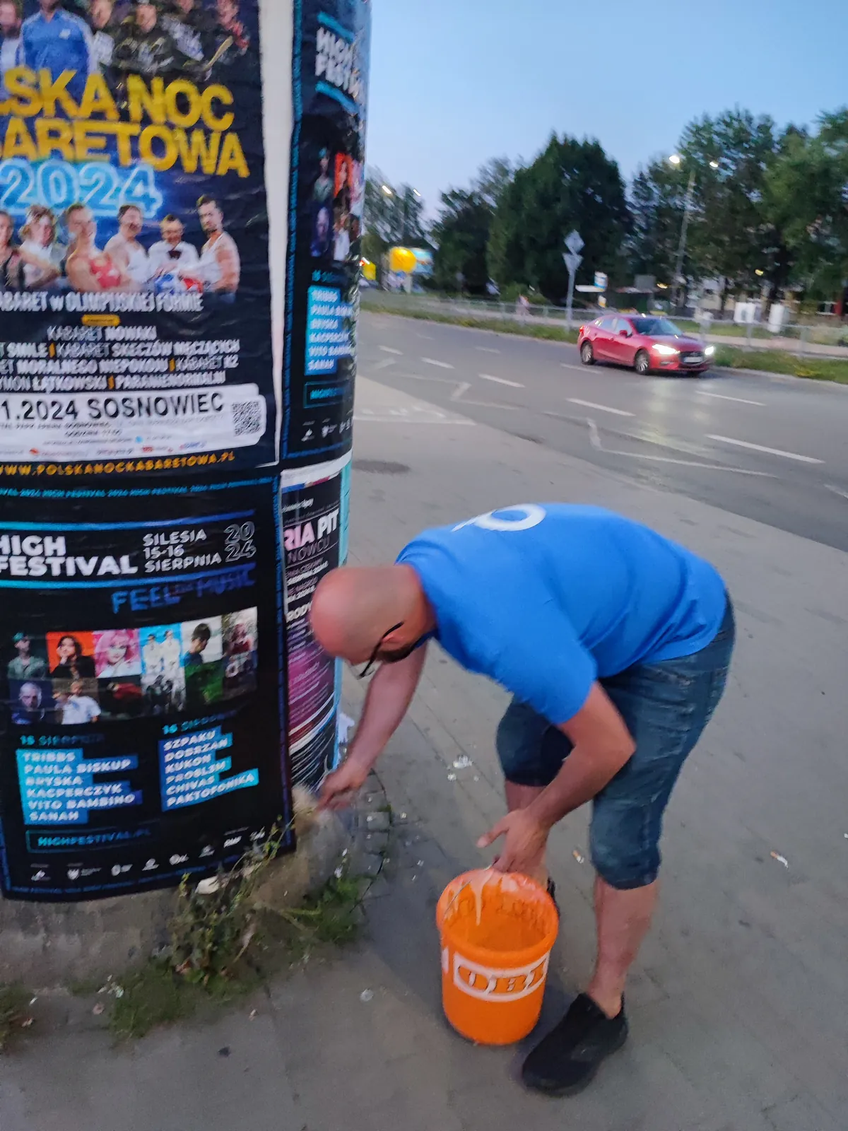 Klejenie plakatów na słupie ogłoszeniowym, klej w wiadrze