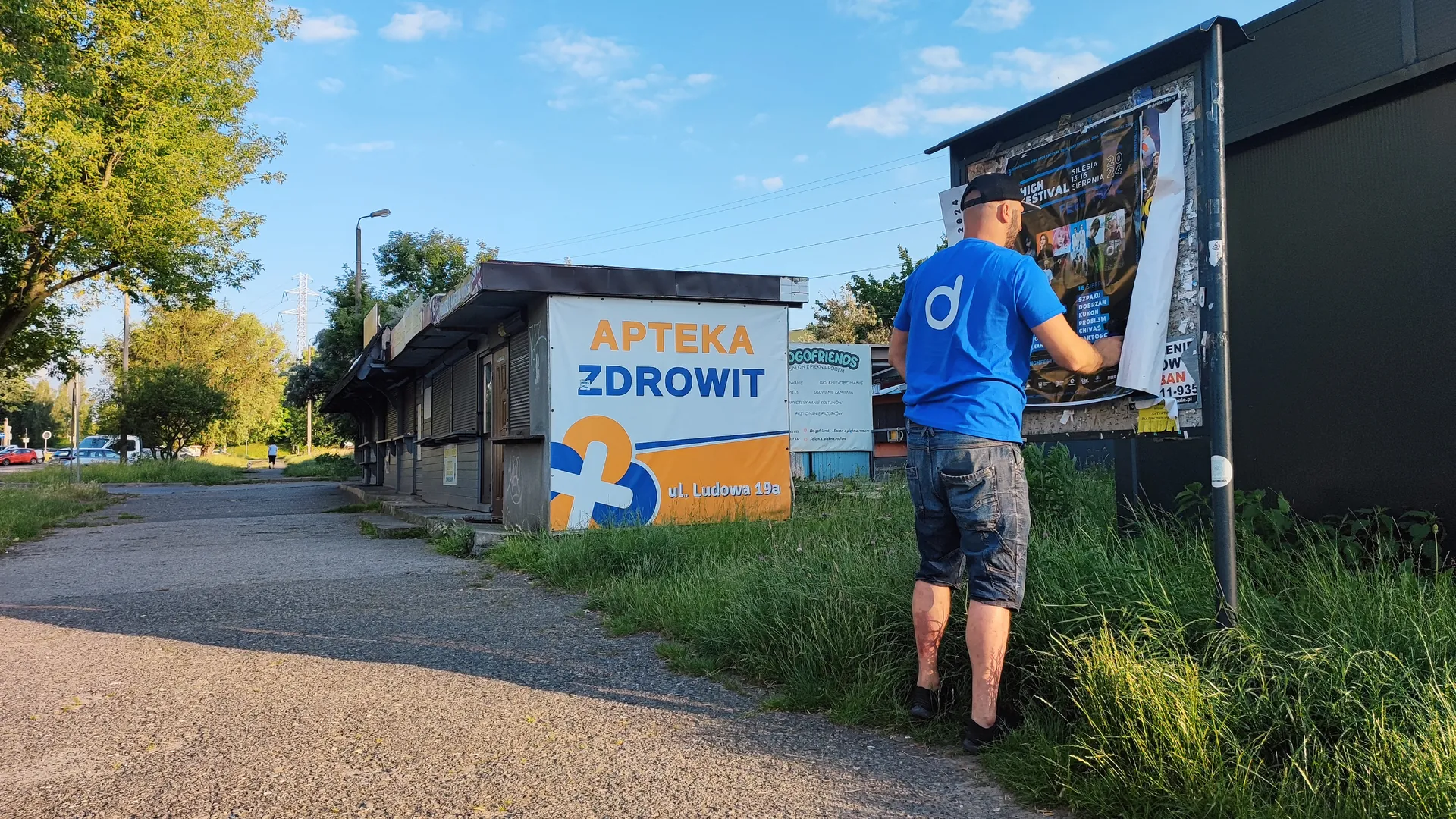 Plakatowanie na tablicy ogłoszeń przy osiedlowej ścieżce