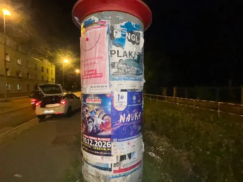 Słup ogłoszeniowy z plakatami przy ulicy w Gliwicach po zmroku