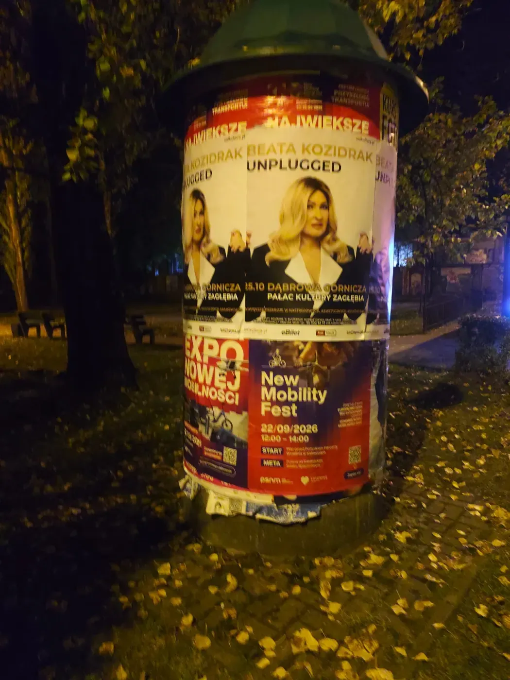 Plakat koncertu Beata Kozidrak Unplugged na słupie wśród innych kolorowych ogłoszeń