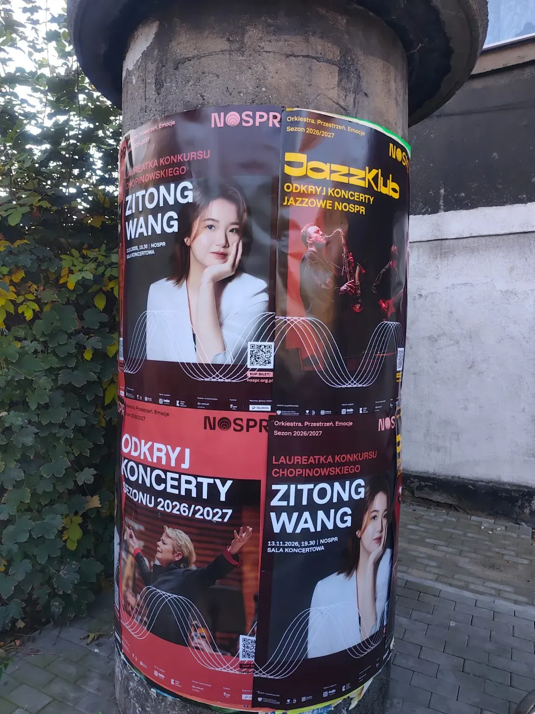 Zbliżenie słupa z plakatem Zitong Wang oraz czarnym plakatem JazzKlub
