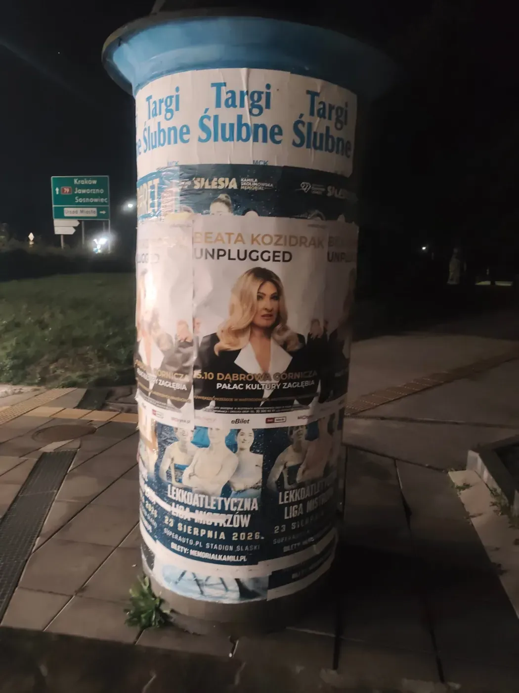 Słup z plakatem koncertu Beata Kozidrak Unplugged przy drogowskazach na Jaworzno i Sosnowiec