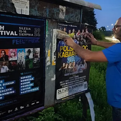 Wieczorne rozwieszanie plakatów na tablicy ogłoszeń przy drodze