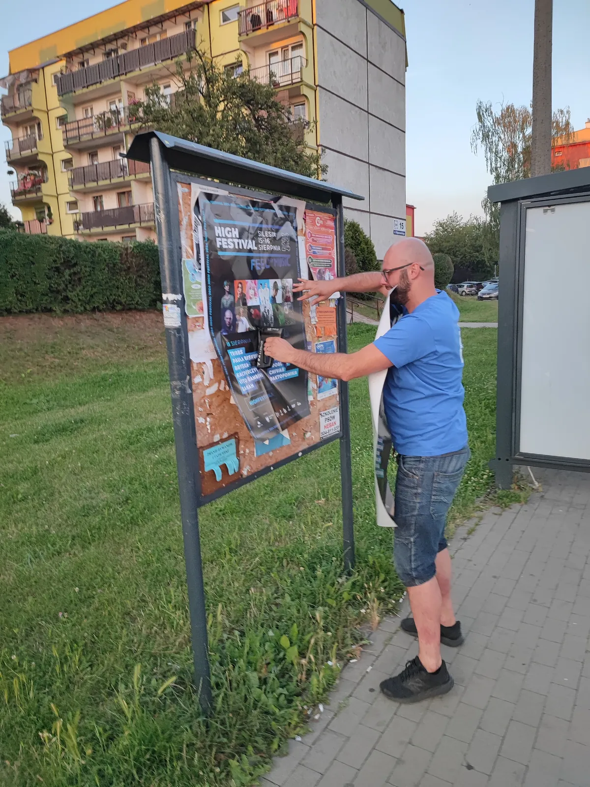 Rozwieszanie plakatu na tablicy przy blokach