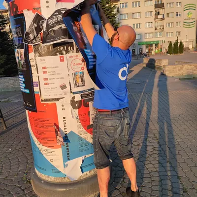 Naklejanie plakatu festiwalu na słupie ogłoszeniowym w Dąbrowie Górniczej
