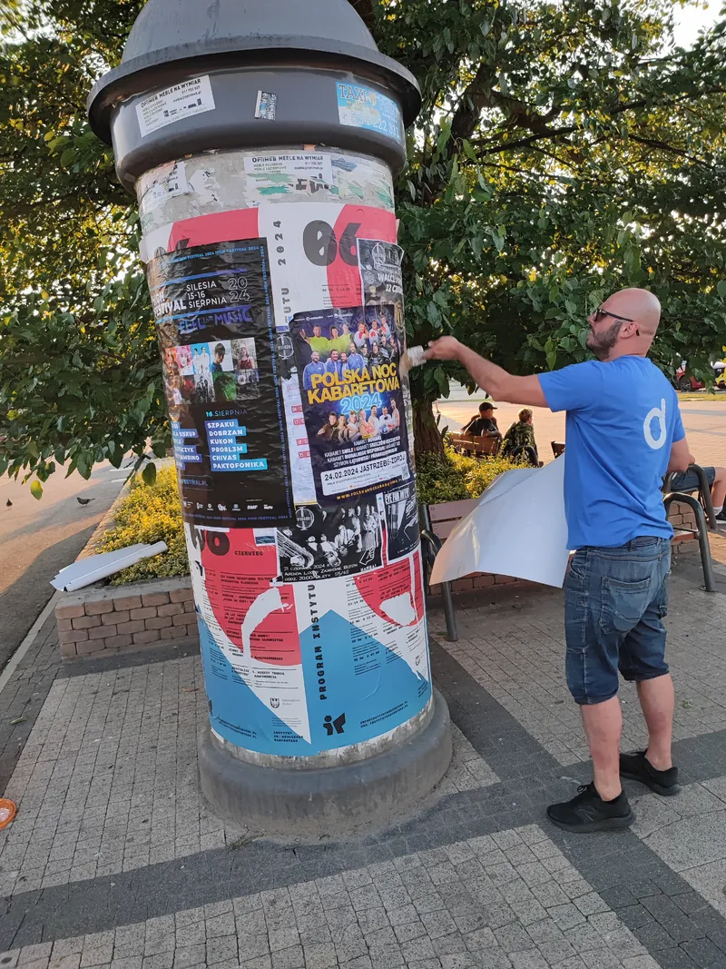 Rozwieszanie plakatów na słupie ogłoszeniowym