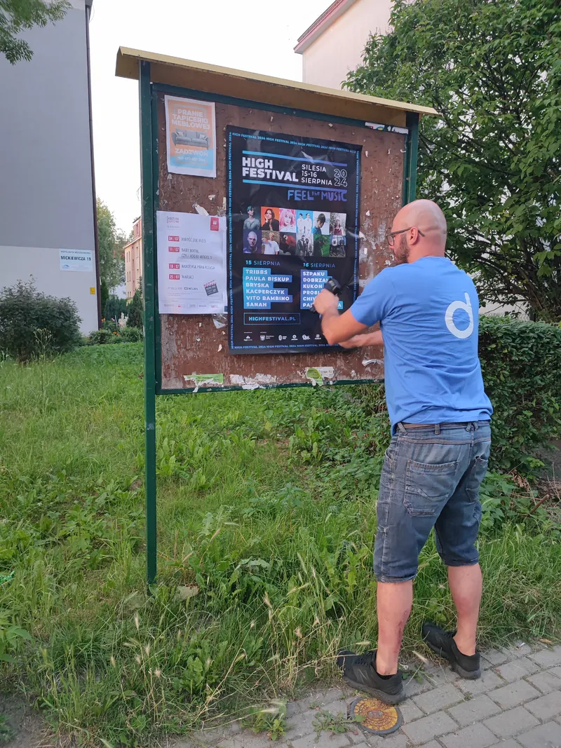 Naklejanie plakatu na ogólnodostępnej tablicy ogłoszeń