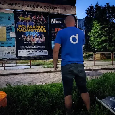Miejska tablica ogłoszeń z naklejonymi plakatami wieczorem