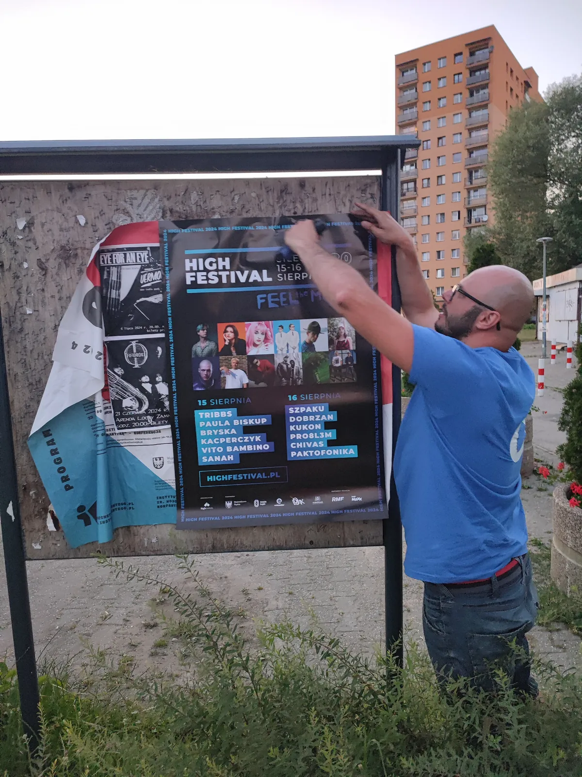 Plakat festiwalu naklejany na tablicy przy bloku